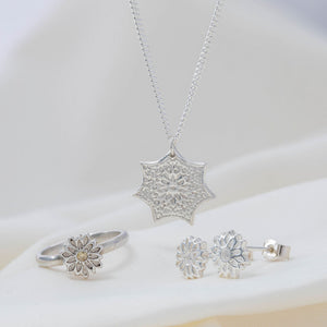 collection of silver jewellery, silver ring with cubic zirconia, silver flow pendant on chain and flower stud earrings.