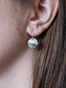 Silver brushed drop earring being worn