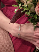 Load image into Gallery viewer, Recycled silver torque bangle with leaf details. Being worn as part of a bridesmaid outfit
